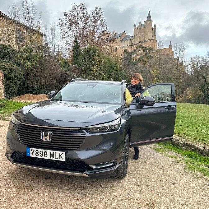 Embajadora subiéndose a un Honda HR-V cerca de un castillo. 